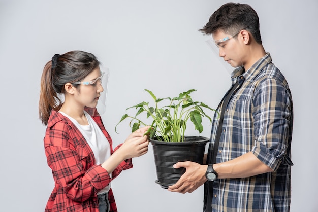 Men and women standing and holding plant pots in the house