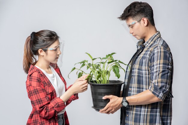 家に植木鉢を立って保持している男性と女性