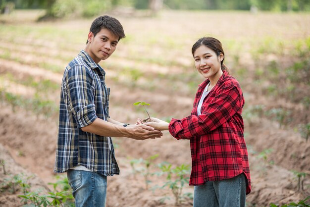 男性と女性が立って苗木を保持しています。