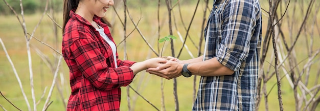 Men and women standing and holding saplings.