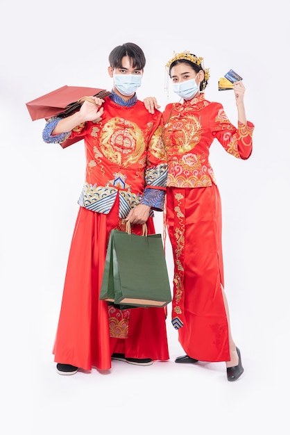 Men and women wear Qipao and wear face masks, carry paper bags, go shopping with credit cards.