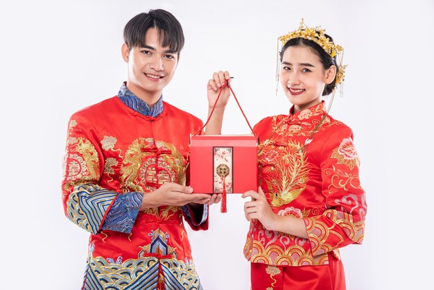 Men and women wearing cheongsam standing with red bags