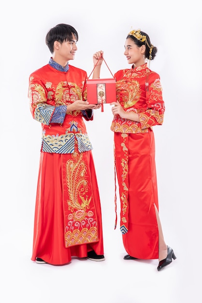 Uomini e donne che indossano cheongsam in piedi con borse rosse