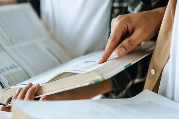 マスクをした男性と女性が立ち、図書館で読書をします。