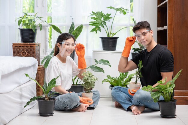 Men and women wearing orange gloves sat and planted trees in a house.