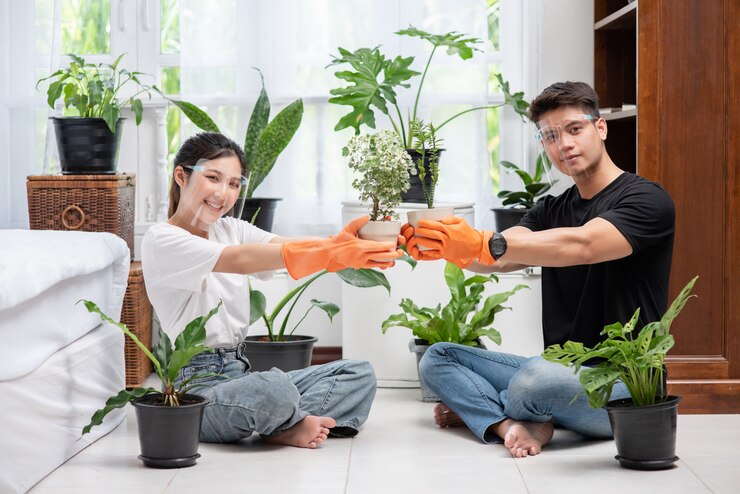 मुफ़्त फोटो men and women wearing orange gloves sat and planted trees in a house.