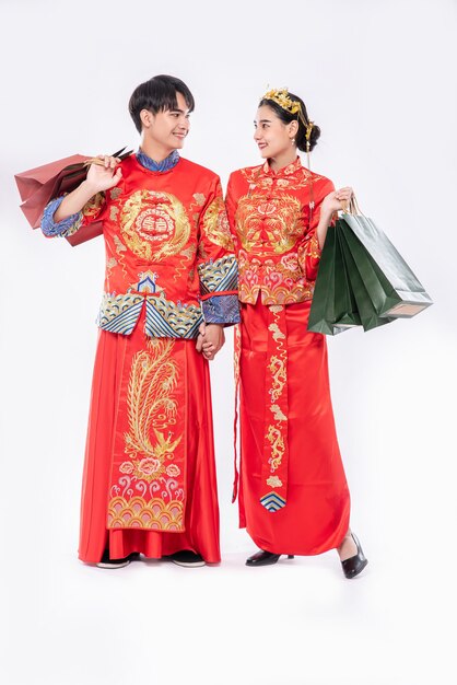 Men and women wearing qipao go shopping with paper bags.