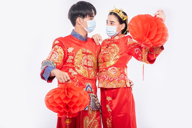 Free photo men and women wearing qipao and wearing face masks stand with honeycomb lamp