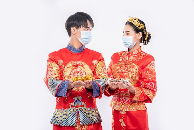 Free photo men and women wearing qipao and wearing masks spend with gold money