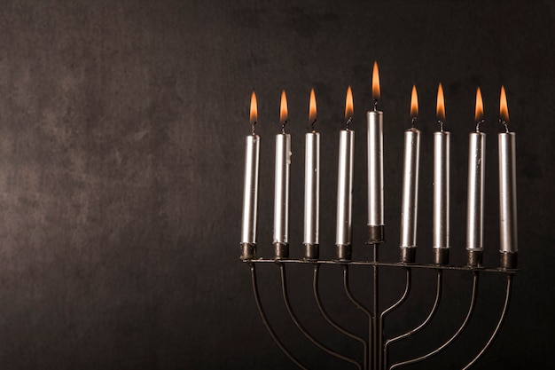 Menorah with candles near gray wall