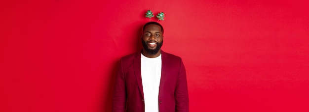 Free photo merry christmas happy african american man celebarting new year wearing funny party headband and smi