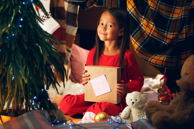 Merry Christmas and Happy Holidays. Cute little child girl writes the letter to Santa Claus near Christmas tree at home indoor. holiday, childhood, winter, celebration concept