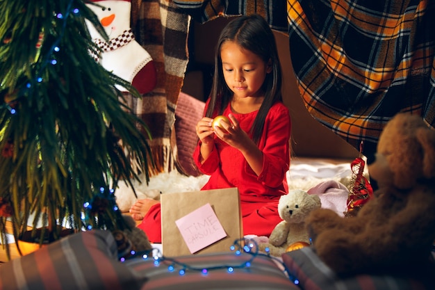 Merry Christmas and Happy Holidays. Cute little child girl writes the letter to Santa Claus near Christmas tree