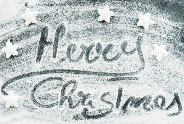 Merry Christmas inscription between decorative snow and stars 