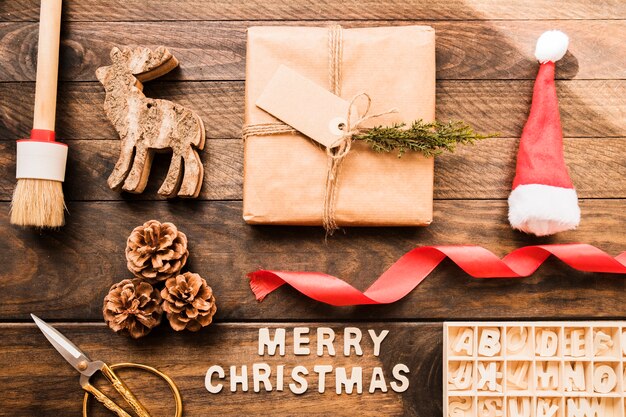 Надпись на рождественскую елку рядом с корягами, буквами и подарочной коробкой