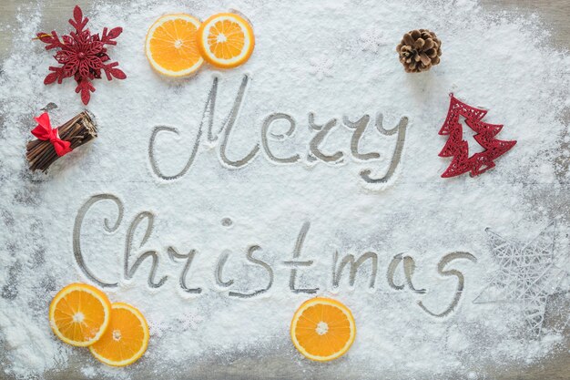 Free photo merry christmas inscription on snow near oranges and decorations