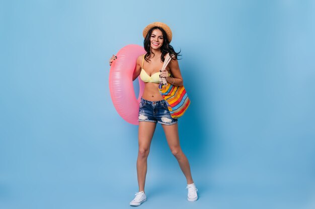 Free photo merry tanned woman in denim shorts dancing on blue background