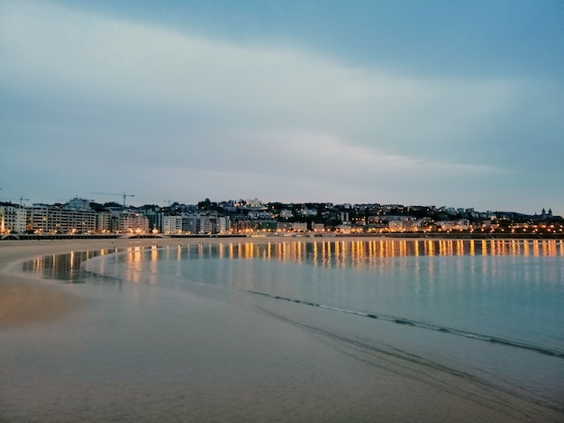 Mesmerizing evening scenery of town lights reflecting in the ocean in San Sebastian, Spain