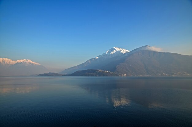 Mesmerizing picture of snow-peaked mountains reflecting on the water under the azure sky