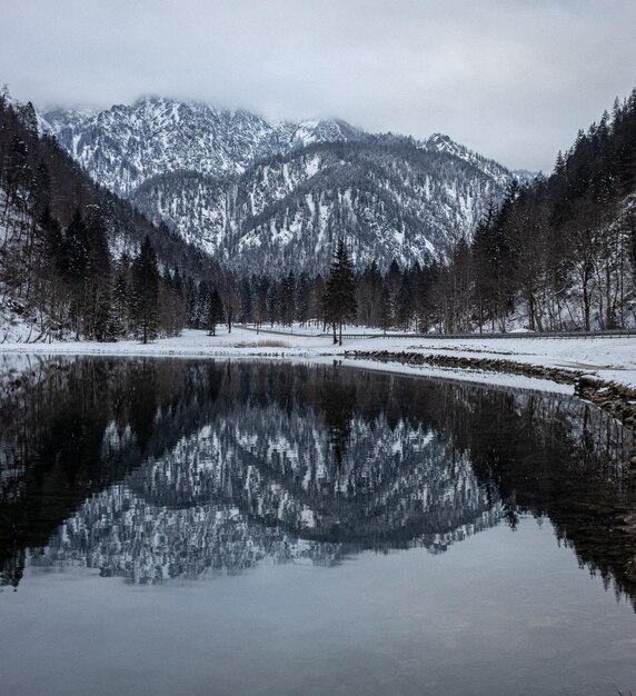 水湖に映るぼんやりとした空の下、雪に覆われた岩だらけの山々の魅惑的なシーン