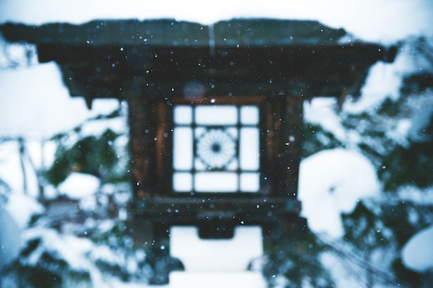 Paesaggio affascinante di neve che cade sopra una lanterna del tempio nel giappone