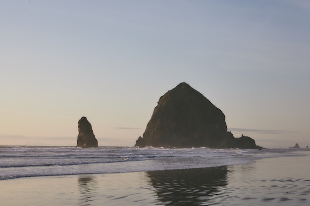 Завораживающие пейзажи заката на скале Haystack Rock в Тихом океане, штат Орегон