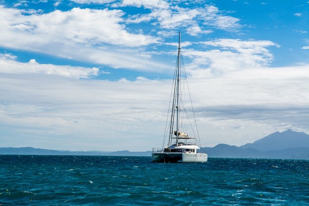 Mesmerizing scenery of a yacht on the blue sea with white clouds in the background