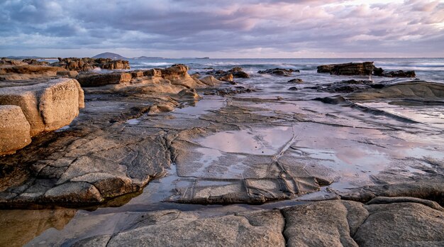 夕日の岩の多い海岸の魅惑的なショット