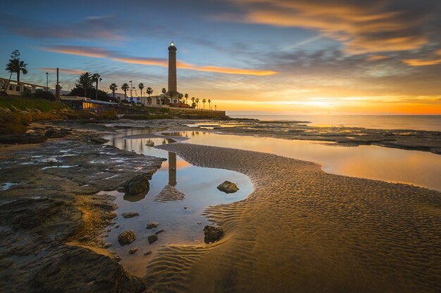 Mesmerizing view of a beautiful seascape with a lighthouse at scenic colorful sunset