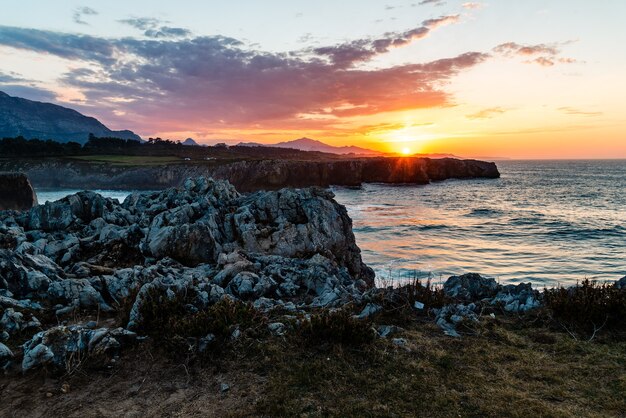日没時に穏やかな海と海岸近くの岩の魅惑的なビュー