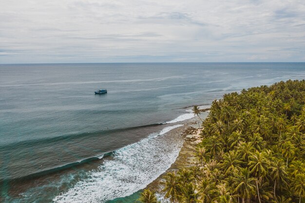 Завораживающий вид на побережье с белым песком и бирюзовой чистой водой в Индонезии.