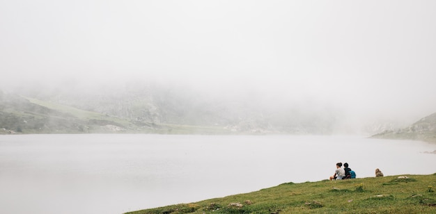Mesmerizing view of the foggy lake with people sitting