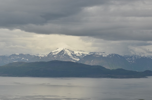 Mesmerizing view of the mountains covered in the snow behind the lake on a gloomy day