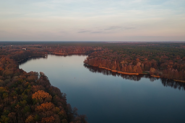 色とりどりの秋の木々に囲まれた穏やかな湖の魅惑的な景色