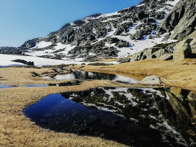 Foto gratuita vista affascinante dell'acqua che riflette l'ambiente circostante nella montagna di penalara in spagna