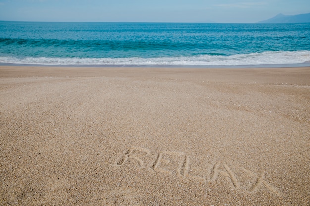 Бесплатное фото Сообщение на песке, говорящее, чтобы расслабиться