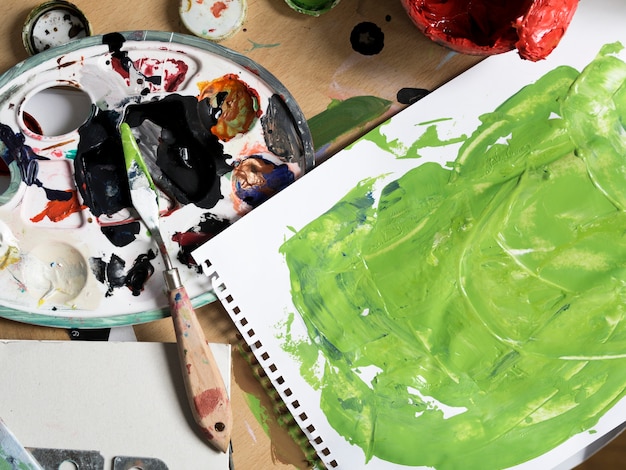 Грязные инструменты рисования рядом с зеленой живописью