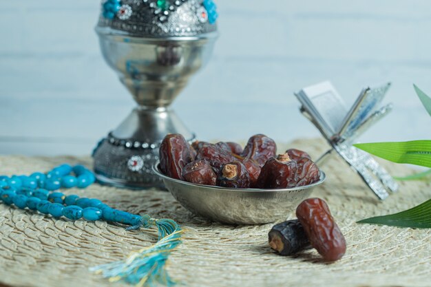 Free photo metal bowl of delicious dates on wooden table.