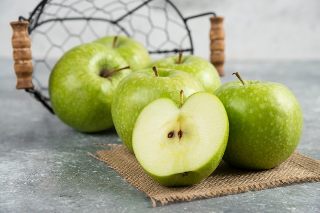 Металлическое ведро свежих зеленых яблок на мраморном столе.