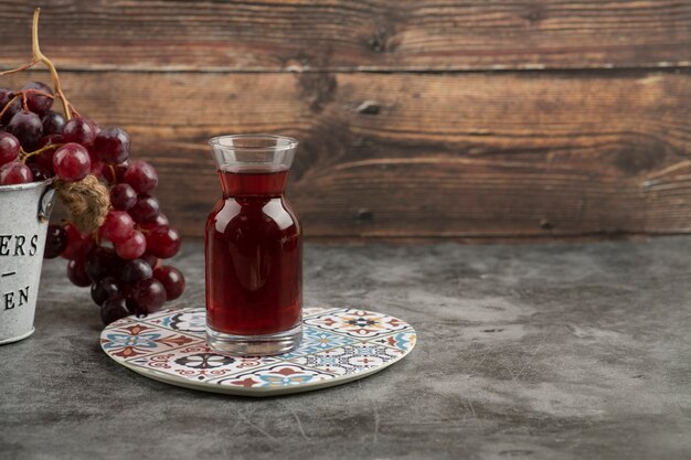 大理石のテーブルに赤い新鮮なブドウとジュースのガラスの金属製のバケツ。
