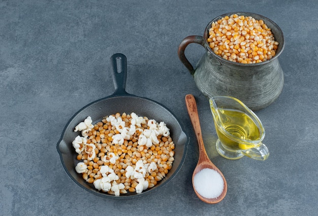 Brocca e padella di metallo piene di chicchi di mais e popcorn schioccati