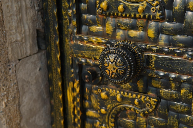 Металлическая старинная дверь с круглой резной ручкой.