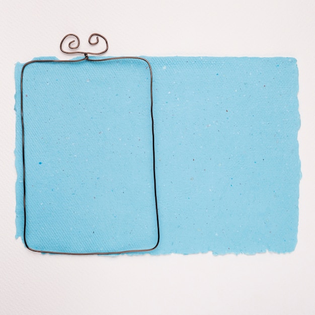 Металлическая пустая рамка на синей бумаге на белом фоне