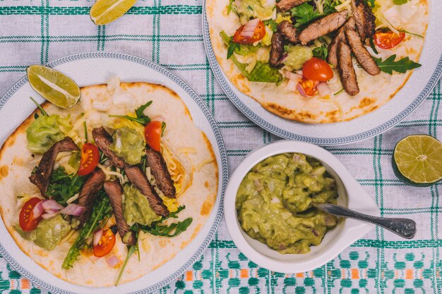 Mexican beef stripes with vegetables in tortilla with guacamole over table cloth