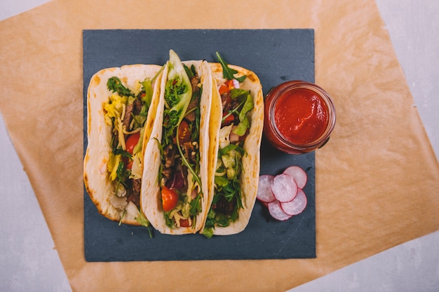 Foto gratuita tacos di manzo messicano con verdure e salsa di pomodoro su ardesia nera