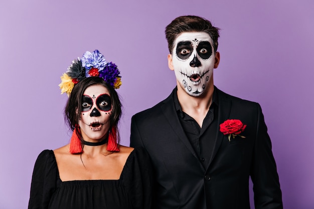 Free photo mexican brown-eyed boy and girl opened their mouths in shock and stared into camera in amazement. snapshot of couple in images of carnival posing on isolated background.