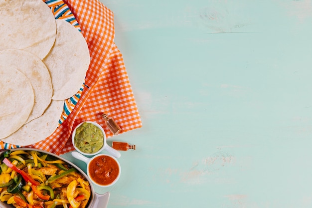 Mexican dish near tortillas and tablecloth