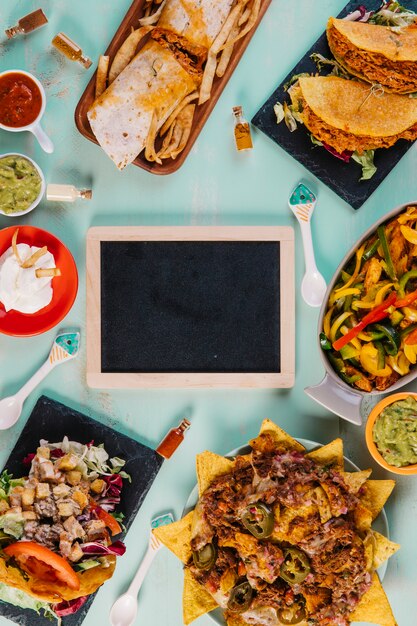 Mexican food around blackboard on blue background