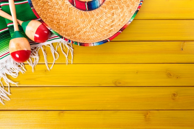 Foto gratuita cappello messicano e maraca sopra pavimento giallo