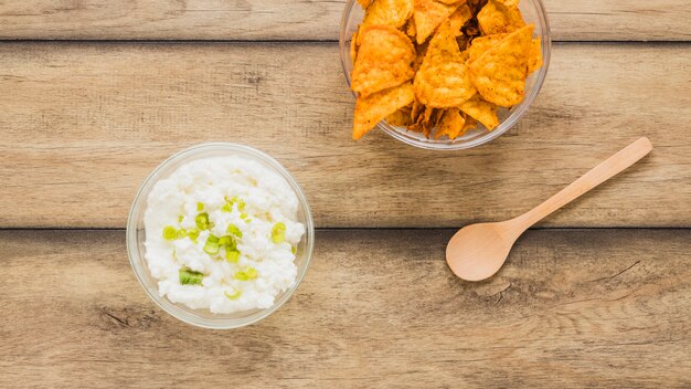 Mexican nachos tortilla chips with cheese dip on wooden table